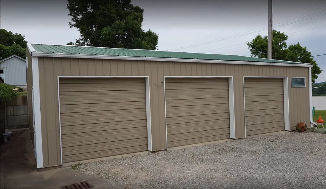 Three-bay detached garage with tan siding and white trim